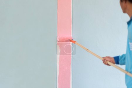 Téléchargez les photos : Peindre la couleur rose sur le mur de ciment à l'aide de rouleau de peinture - en image libre de droit