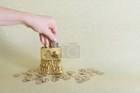 Foto de Una gran cantidad de monedas de euro cerca de una alcancía en forma de una casa de oro. Concepto de ahorro de dinero. Foto de alta calidad - Imagen libre de derechos
