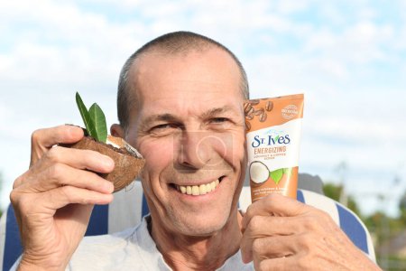 Téléchargez les photos : ST. Ives Fresh Energizing Coconut and Coffee Scrub in Tube, homme d'âge moyen démontre gommage du visage, Comme, Belgique, 13 août 2022, photo de haute qualité - en image libre de droit