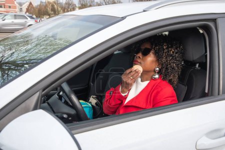 Photo for Pretty african woman in a car doing makeup while standing in a traffic jam, concept a modern married business woman with children saves time, High quality photo - Royalty Free Image