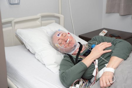 Mujer de mediana edad que mide las ondas cerebrales, examinando la polisomnografía en el laboratorio del sueño, Foto de alta calidad