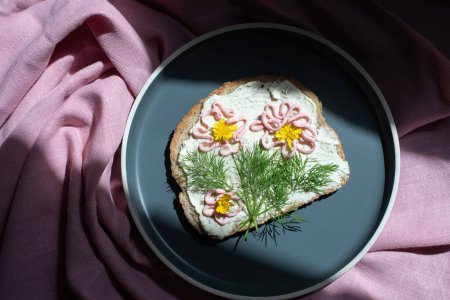 Téléchargez les photos : Creative sandwich with soft cheese and pink pasta tarama greens, flowers are drawn on the sandwich. High quality photo - en image libre de droit