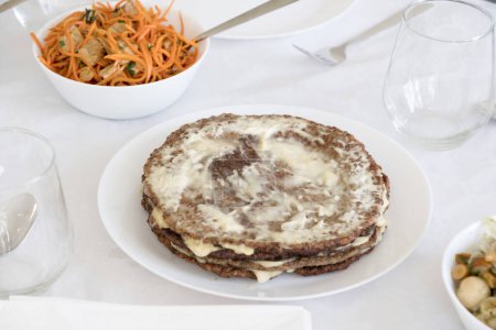 Téléchargez les photos : Gâteau au foie traditionnel festif, tarte à l'ail et mayonnaise sur la table pour les vacances avec des carottes coréennes dans des saladiers, photo de haute qualité - en image libre de droit