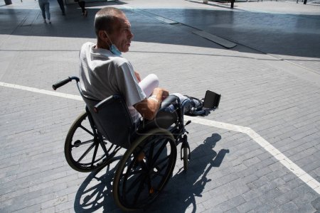 Hombre de mediana edad con una pierna rota en un yeso en una silla de ruedas en un paseo cerca del hospital. Foto de alta calidad