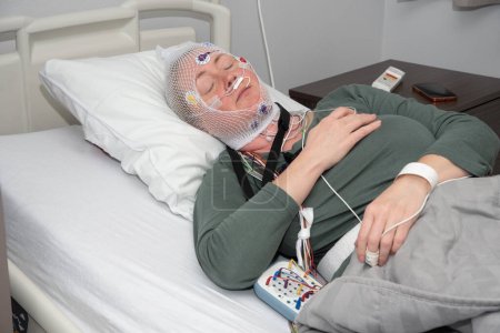 Mujer de mediana edad que mide las ondas cerebrales, examinando la polisomnografía en el laboratorio del sueño, Foto de alta calidad