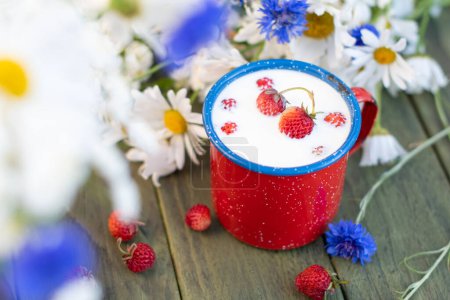 Photo for Fresh Strawberry with cold milk in red mug on wild flowers background,childhood nostalgia Healthy fruit dessert, food and drink, High quality photo - Royalty Free Image