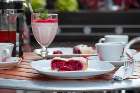 Téléchargez les photos : Délicieux dessert Cherry strudel sur une table dans un café de rue avec milkshake aux fruits, cadre de table élégant, photo de haute qualité - en image libre de droit