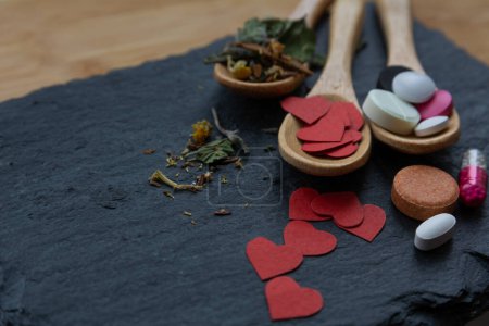 Foto de Armonía de la curación con el amor: cucharas de madera con hierbas medicinales, corazones de papel y drogas (cápsulas, tabletas) - concepto para el Día de San Valentín - Imagen libre de derechos