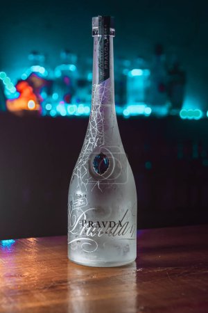 Foto de Buenos Aires, Argentina; 30-07-2023: Imagen vertical de una botella de vodka Pravda sobre una mesa de madera en un bar. - Imagen libre de derechos
