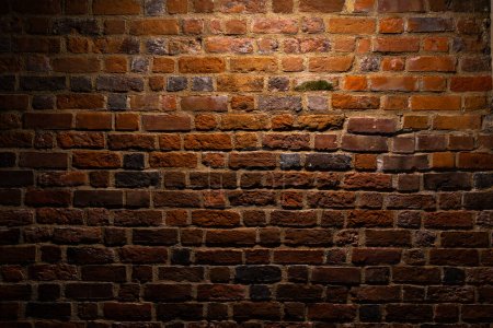 Photo for A red brick wall illuminated at night. Surface texture emphasized by the angle of incidence of light - Royalty Free Image