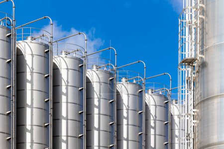Stainless steel silos against the blue sky. Warehouses for storage of plastics and bulk grains.