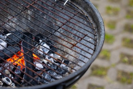 Téléchargez les photos : Foin d'un grill en métal avec flamme de charbon de bois. Préparation du barbecue dans le jardin. - en image libre de droit
