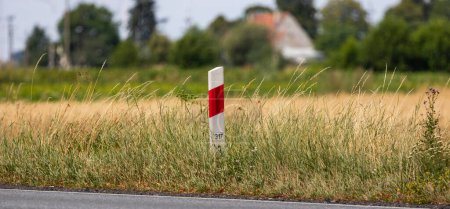 Photo for Mileage bars at the edge of the road. Picture taken on a sunny day, blurred background behind the subject - Royalty Free Image