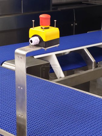 Emergency safety buttons in the stainless steel conveyor system with blue polyurethane, modular belt. Transport systems in industrial factories.