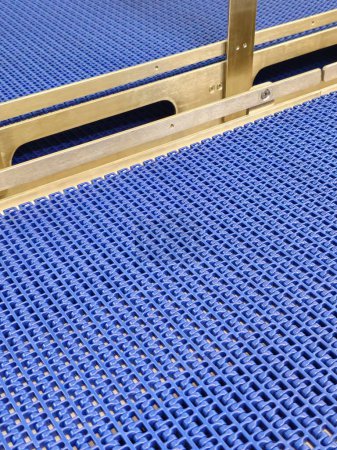 Nahaufnahme eines blauen Polyurethan-Gurtes in einem modularen industriellen Fördersystem. Transportsysteme aus rostfreiem Stahl in Industriebetrieben.