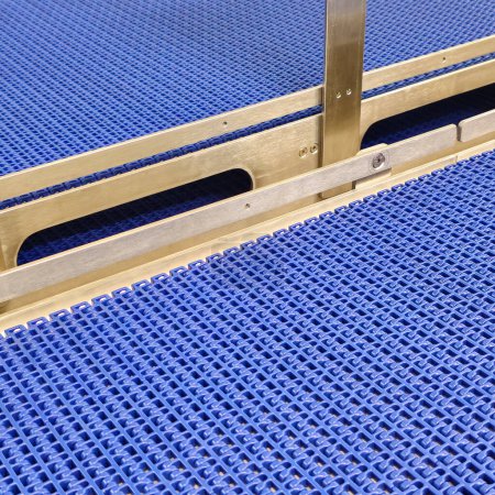 A close-up of a blue polyurethane belt in modular industrial conveyor system. Stainless steel transport systems in industrial factories.