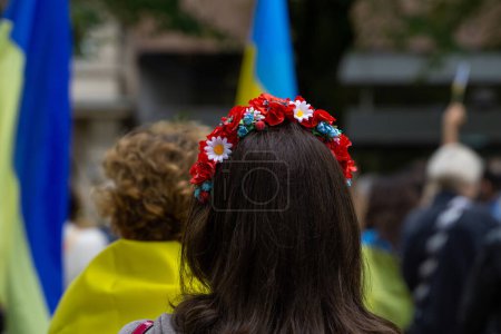 Photo for Closeup of a woman wearing a traditional Ukrainian head band and Ukrainian flags on the background - Royalty Free Image