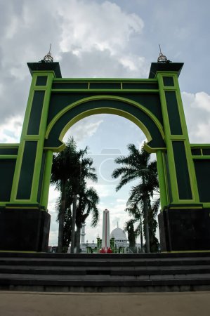 Téléchargez les photos : La porte d'entrée verte avec un fond de palmier sur la place de la ville de Pasuruan, Indonésie - en image libre de droit