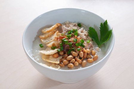 Bubur Ayam Original enthält weißen Reisbrei mit Beilagen aus gebratenen Hühnerscheiben, gebratenen Sojabohnen, leerem Cracker und bestreut mit gebratenen Zwiebeln und Sellerie