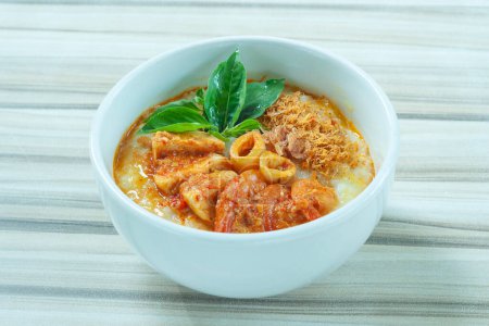 Seafood porridge consist of white rice porridge, shrimp, squid, sliced beef. served in a bowl