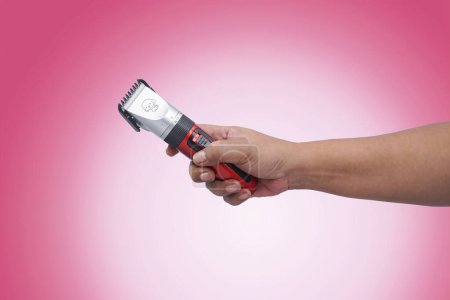 close up of a hand hold a fur clipper. Isolated on red background