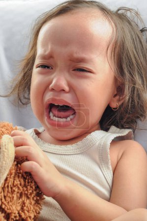 Téléchargez les photos : Portrait d'une petite fille indonésienne pleurant à haute voix. isolé sur fond plat - en image libre de droit