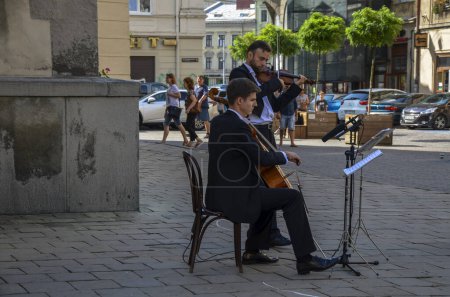 Photo for Buskers: Two classical variety street musicians play violin and cello in the street of the city Lviv, Ukraine - Royalty Free Image