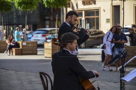Téléchargez les photos : Buskers : Deux musiciens de rue classiques jouent du violon et du violoncelle dans la rue de la ville Lviv, Ukraine - en image libre de droit