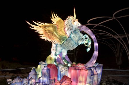 Leuchtend farbige Skulptur des Fabelwesens Pegasus steht auf farbigen Bergen oder Felsen und schafft ein illuminiertes Märchen aus Licht