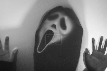 Photo for Bangkok, Thailand - August, 18, 2023 : Shadow blur of horror man in screaming mask.Dangerous man behind the frosted glass.Mystery man.Black and white picture.Blur picture.Add effects noise and grain.Halloween. - Royalty Free Image