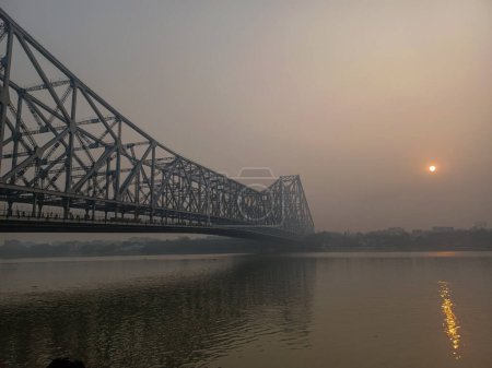 Téléchargez les photos : Kolkata, Inde, 26 février 2024 : Pont historique Howrah Kolkata au lever du soleil avec vue sur le ghat du Gange. Howrah bKolkata, Inde, 26 février 2024 : Pont historique Howrah Kolkata au lever du soleil avec vue sur le ghat du Gange. Pont Howrah est un célèbre - en image libre de droit