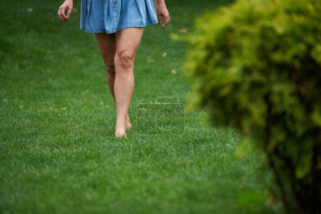 Erwachsene Frau läuft barfuß auf dem Gras im Park