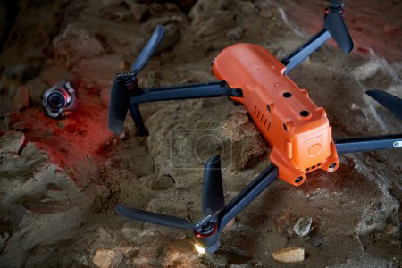 Kaputter orangefarbener Quadrocopter auf Steinen
