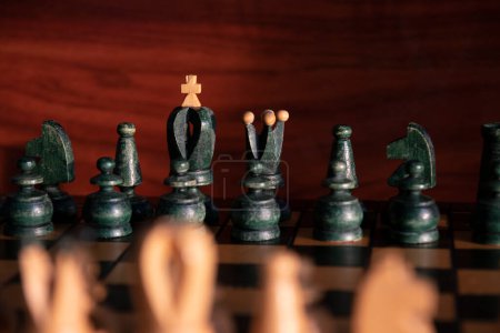 Foto de Tablero de ajedrez con damas negras en el fondo y damas blancas fuera de foco sobre un fondo de madera marrón. Concepto: ajedrez - Imagen libre de derechos