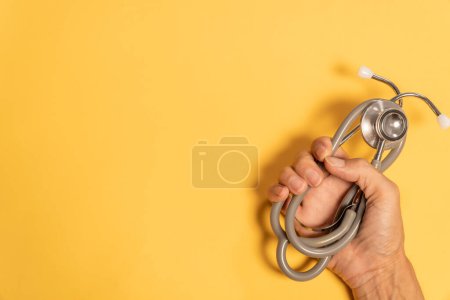 Photo for Hand holding Single Head Stethoscope on yellow background - Royalty Free Image