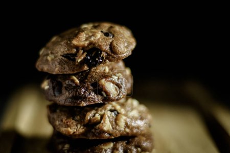 Foto de Galletas caseras de chocolate dulce sobre mesa de madera con fondo negro - Imagen libre de derechos