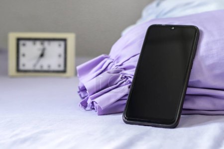 Foto de Un smartphone negro en la cama púrpura - Imagen libre de derechos
