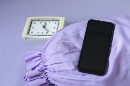 Téléchargez les photos : Un smartphone noir sur lit violet - en image libre de droit
