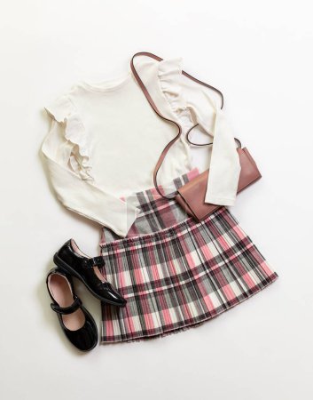 Photo for 8 year old Girl clothes, white blouse and plaid skirt, black shoes, small pink , bag on white background. - Royalty Free Image