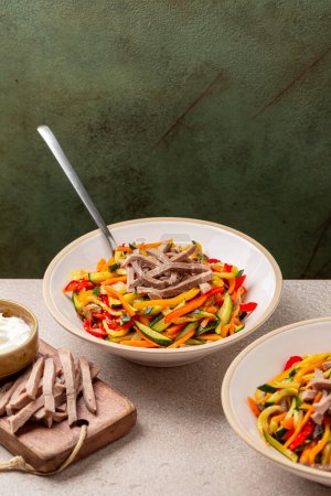 Photo for Beef tongue meat salad with marinated vegetables, bell pepper, zucchini, celery, onion, carrot. Vertical image. - Royalty Free Image
