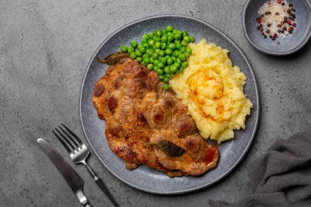 Foto de Top view of fried pork steaks with spices and sage, mashed potato and boiled green peas. Copy space, grey background. - Imagen libre de derechos