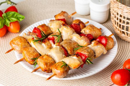 Photo for Chicken, italian sausage, bacon and vegetable, bell peppers kebabs or skewers. Mediterranean kabob food on a white plate with rosemary. - Royalty Free Image
