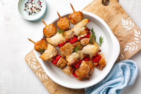 Photo for Mix meat skewers directly above. Chicken, italian sausage, bacon and vegetable, bell peppers kebabs. Mediterranean kabob, summer food on a white plate with rosemary. - Royalty Free Image