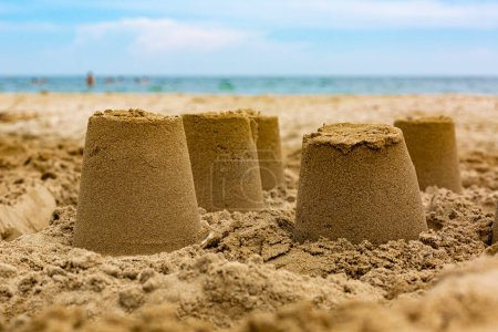 Téléchargez les photos : Châteaux de sable sur la plage, mer bleue et ciel. Concept vacances d'été. - en image libre de droit