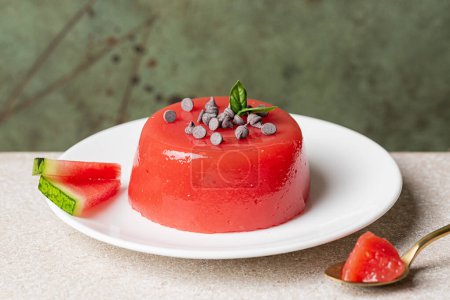 Photo for Sicilian summer dessert gelo di melone, Italy. A jellied watermelon pudding, made with watermelon pulp, sugar and starch, decorated with chocolate and basil leaves. Green background. - Royalty Free Image