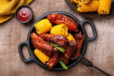 Photo for Food board with baked pork ribs with corn cobs, barbecue sauce, rosemary. Meat dinner. Brown table background, top view. - Royalty Free Image
