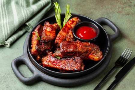 Photo for Plate with baked pork ribs with barbecue sauce, rosemary. Green table background. Meat food. - Royalty Free Image