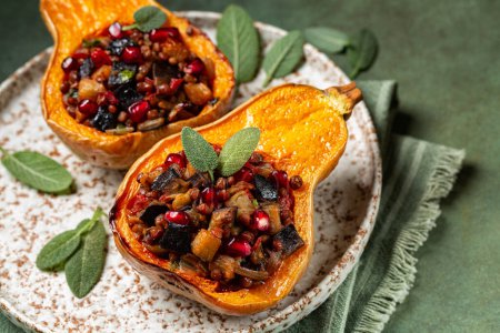 Photo for Roast stuffed butternut pumpkin with lentil, eggplant, tomato, onion and pomegranat. Oven baked vegetables, vegetarian or vegan food on a green background. - Royalty Free Image
