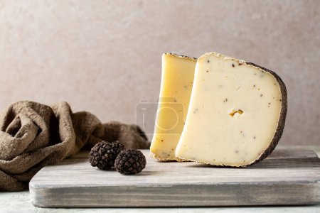 Photo for Wooden board with aged sheep's milk pecorino cheese with black truffles flakes. Fresh whole truffles on a board. Italian luxury cheese. Copy space. - Royalty Free Image