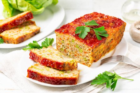 Photo for Homemade meatloaf or terrine with mix of chicken and turkey meat, carrot, leek and green peas, glazed with ketchup. Baked minced chicken meat. White table surface, vertical image. - Royalty Free Image